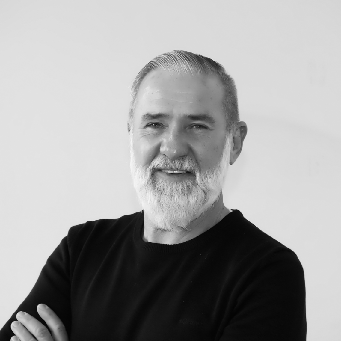 Thomas Gruber- Sachverständiger Ein älterer Mann mit grauem Bart und lächelndem Gesicht, trägt ein schwarzes Shirt.